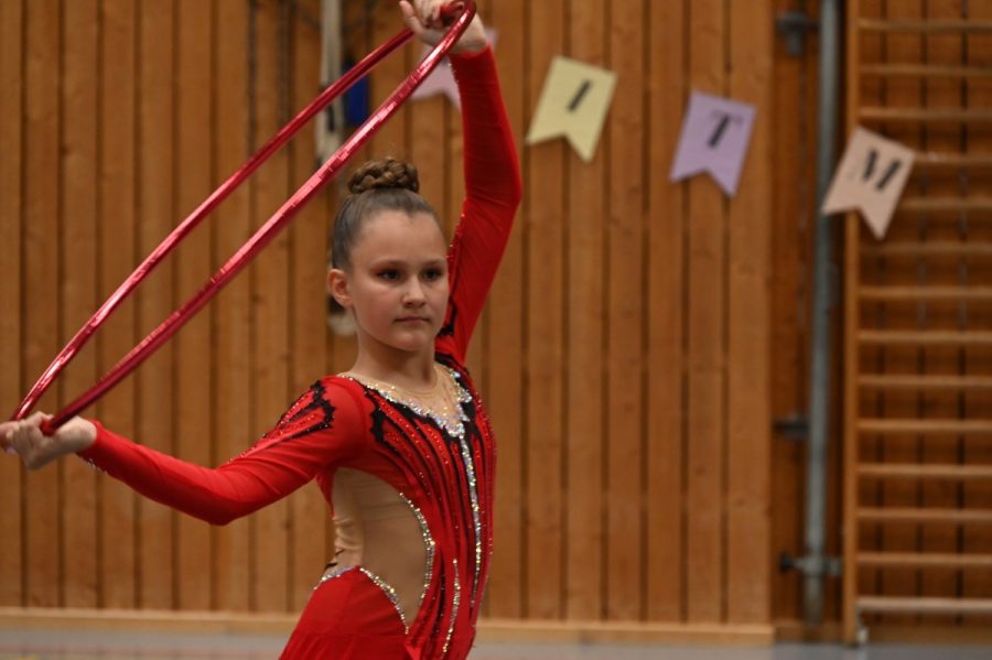Eine Gymnastin hält einen Reifen in den Händen und blickt in die Kamera.