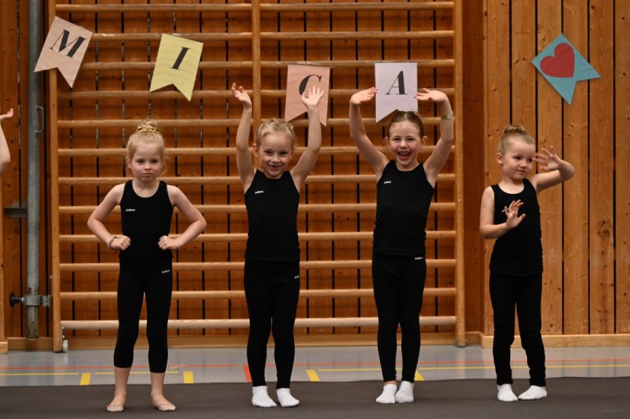 Vier Mädchen stehen in einer Sporthalle nebeneinander und heben die Arme.