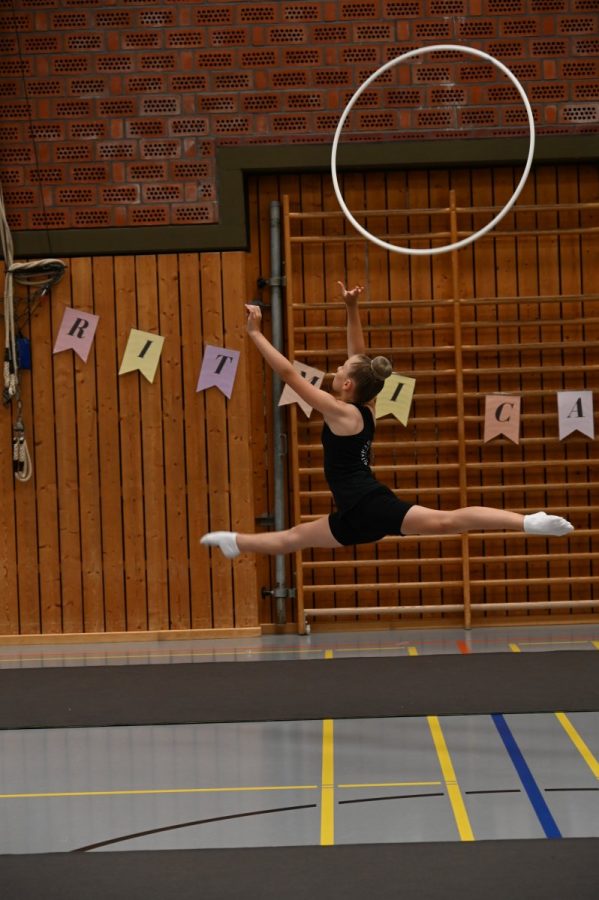 Eine Gymnastin springt in einer Sporthalle mit einem Reifen.