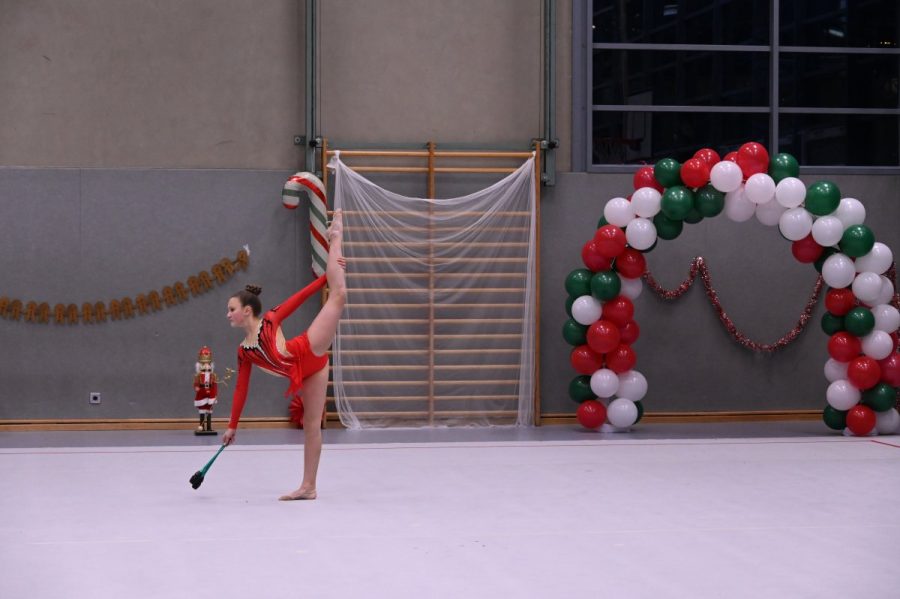 Eine Gymnastin zeigt eine Übung mit einer Keule in der Sporthalle.