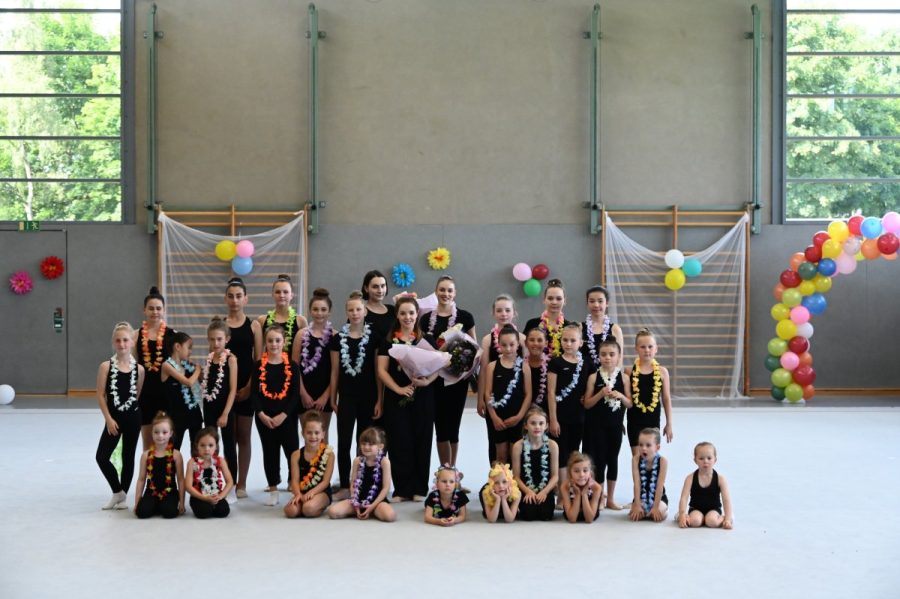 Eine große Gruppe von Gymnastinnen versammelt sich in der Sporthalle.