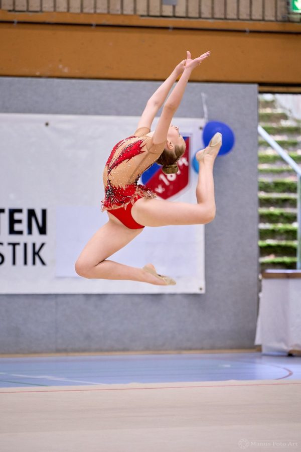 Eine Gymnastin zeigt in der Luft einen Sprung.