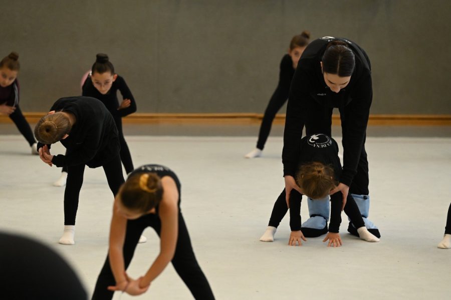 Eine Gruppe Mädchen beim Dehntraining in einer Sporthalle.