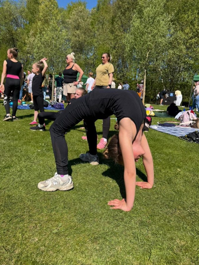 Eine Gymnastin zeigt eine Rückwärtsbrücke auf einer Wiese im Freien.