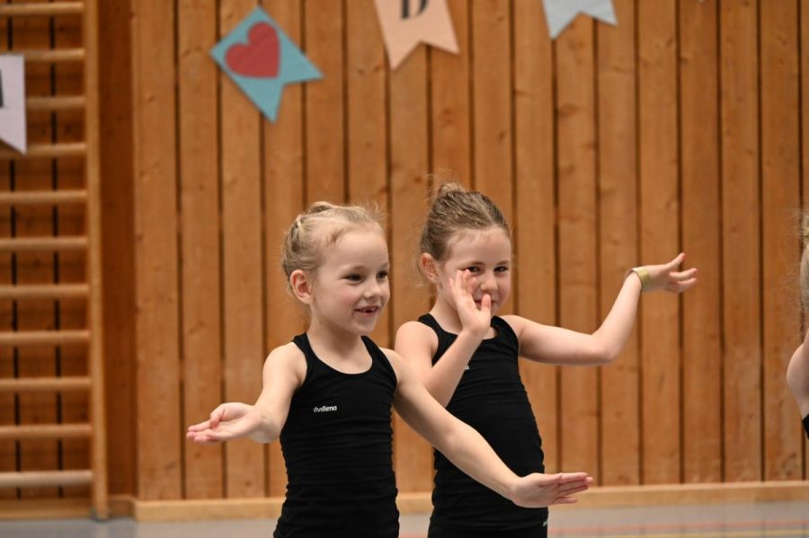 Zwei kleine Gymnastinnen in Turnkleidung lächeln in die Kamera.