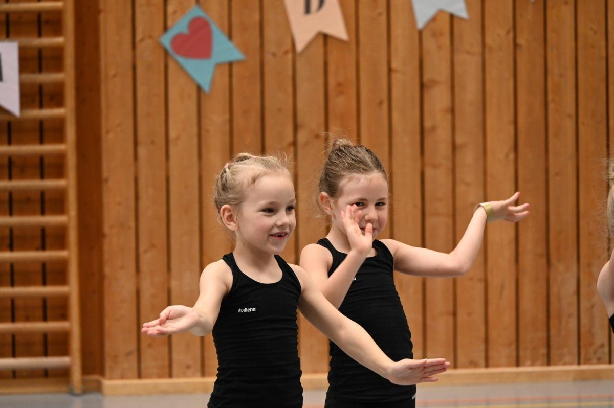 Two young gymnasts in sportswear smiling at the camera.