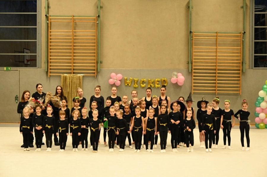 Eine Gruppe Mädchen in einheitlicher Sportkleidung posiert in einer Turnhalle.