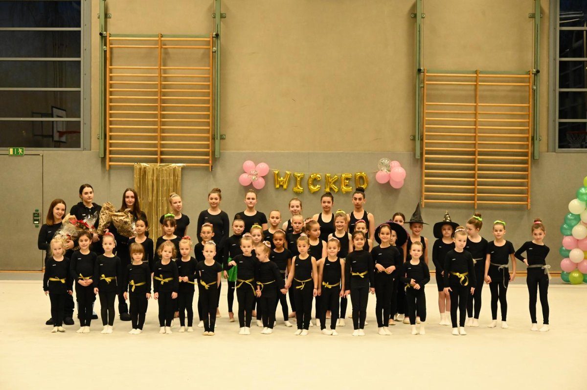 Eine Gruppe Mädchen in einheitlicher Sportkleidung posiert in einer Turnhalle.