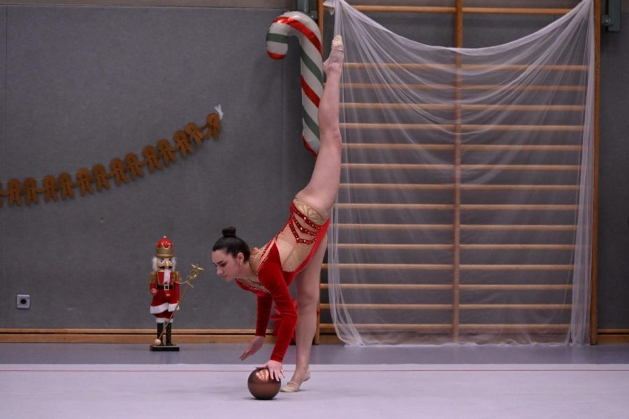 Eine Gymnastin zeigt eine Balanceübung mit einem Ball in der Halle.