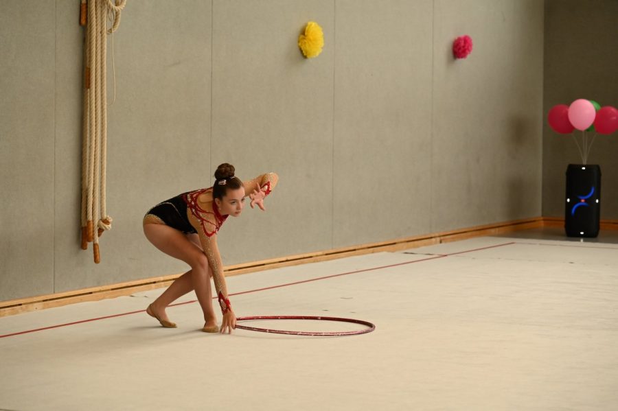 Eine Gymnastin bei einer Übung mit dem Reifen in einer Sporthalle.