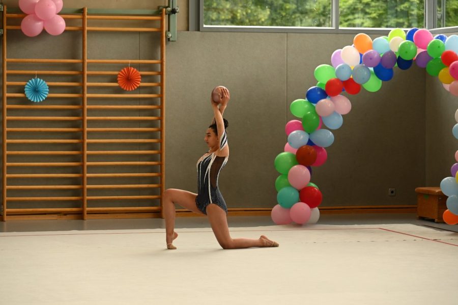 Eine Gymnastin kniet auf der Matte und hält einen Ball.