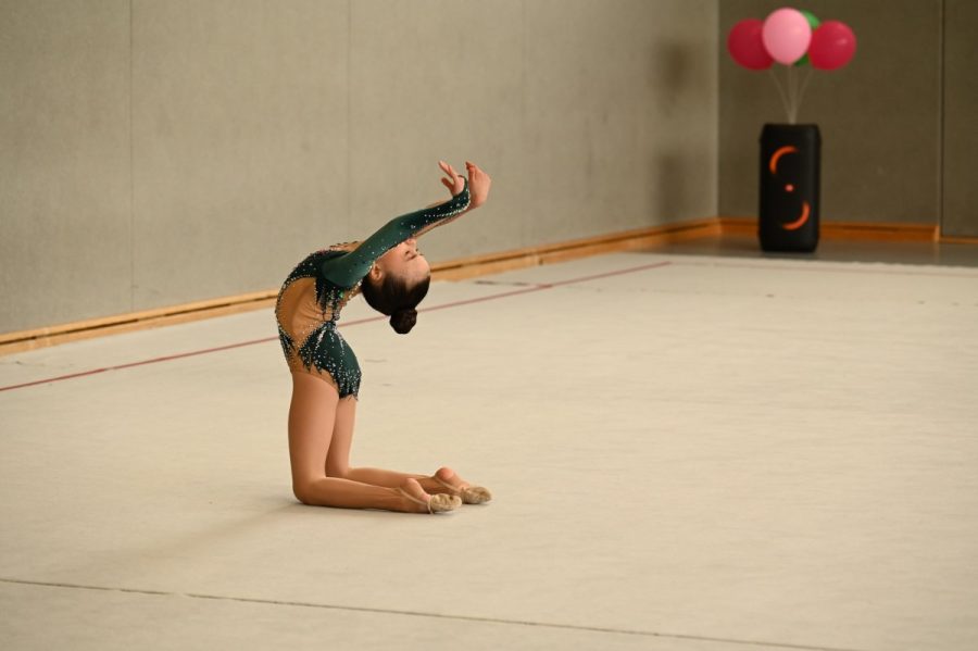 Eine Gymnastin zeigt eine Rückbeuge im Kniestand auf der Gymnastikfläche.