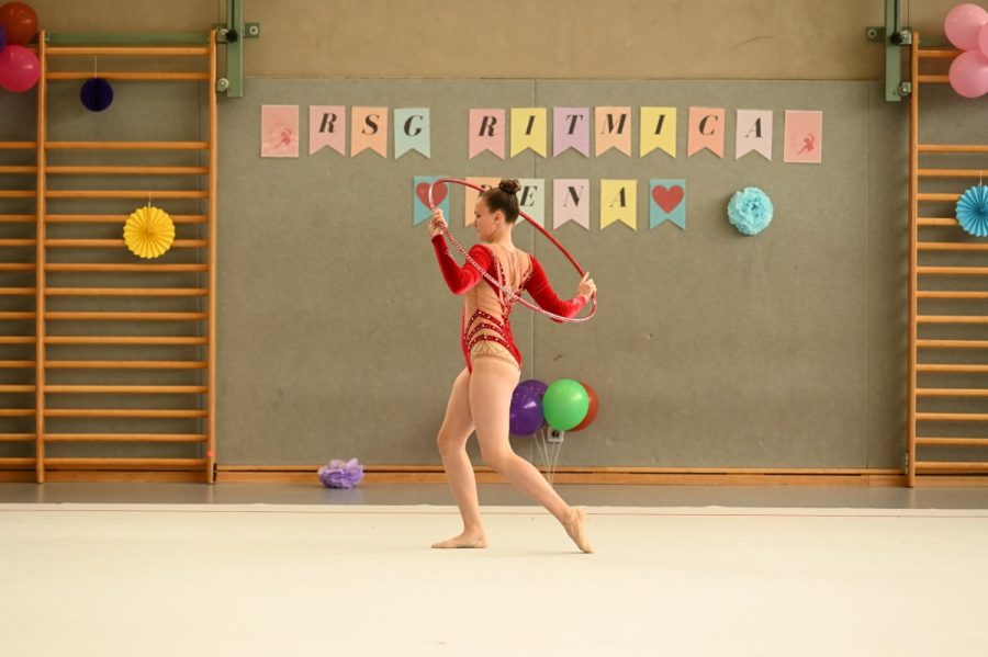 Eine Gymnastin zeigt in einer Sporthalle eine Übung mit dem Reifen.