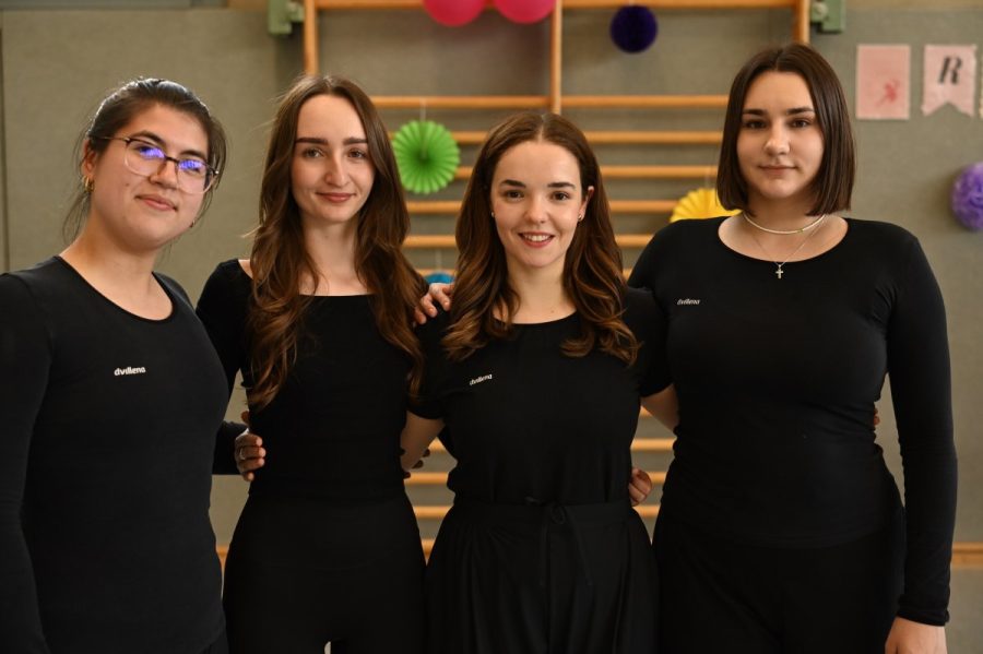 Vier junge Frauen stehen nebeneinander in einer Sporthalle.
