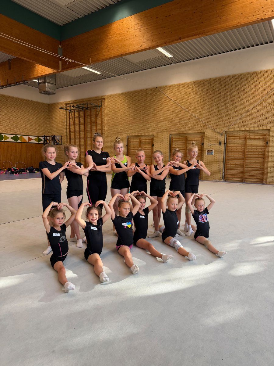Eine Gruppe von Gymnastinnen formt gemeinsam mit den Händen Herzen.