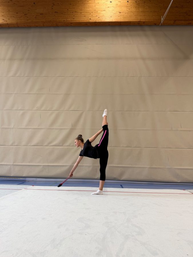 Eine Gymnastin zeigt eine Standwaage in der Sporthalle.