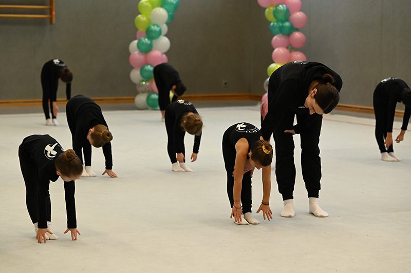 A group of girls stretching in a sports hall.